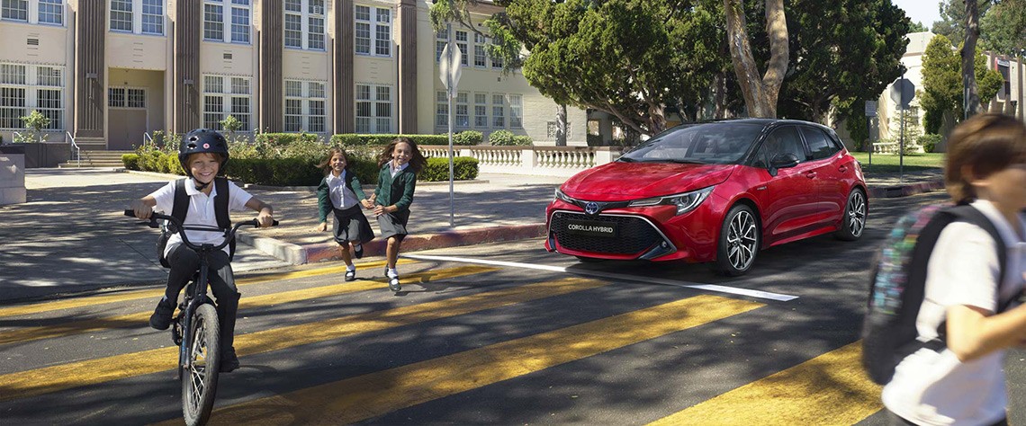 Kinder wechseln die Straße vor einem wartenden Toyota Corolla Hybrid
