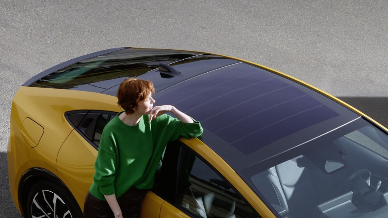 Frau steht an einem Toyota Prius mit Solardach