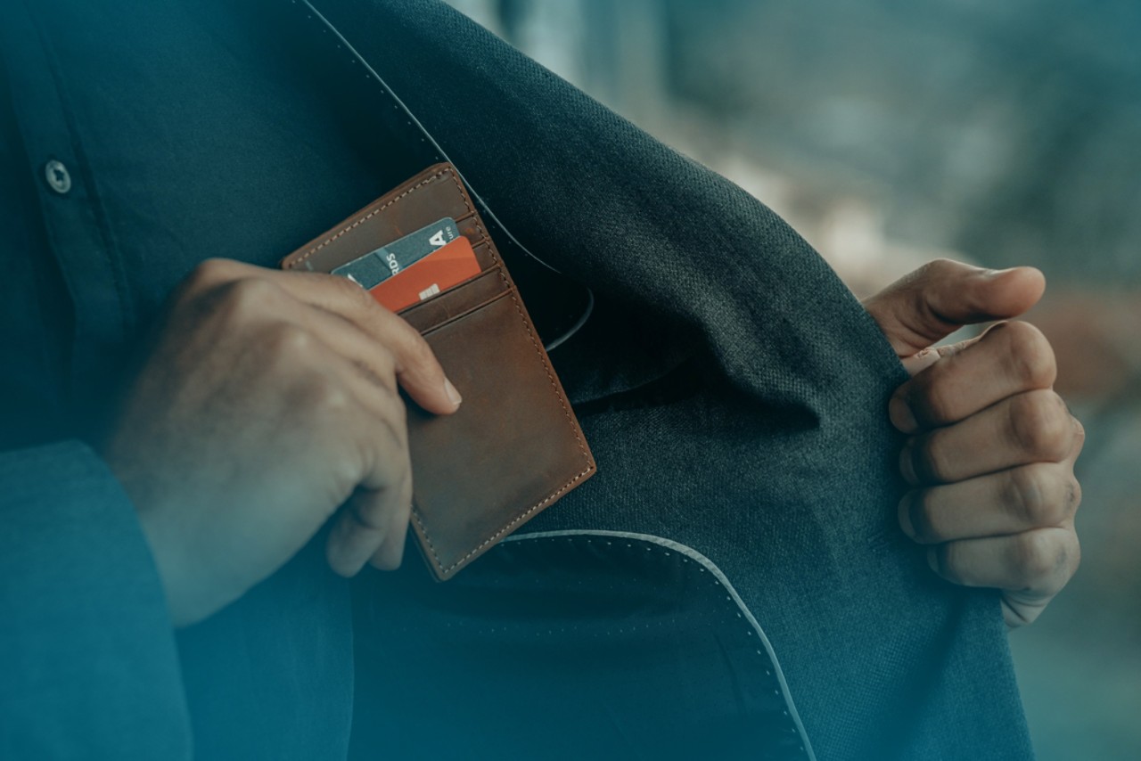 Eine Person steckt eine Brieftasche in die Innentasche eines Jackets