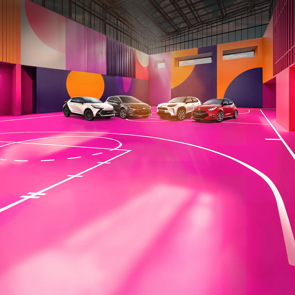Ein weißer Toyota C-HR, ein grauer Corolla, ein weißer Yaris Cross und ein roter Yaris stehen auf einem bunten, mit lilanen, roten und blauen Mustern versehenen Basketballplatzes