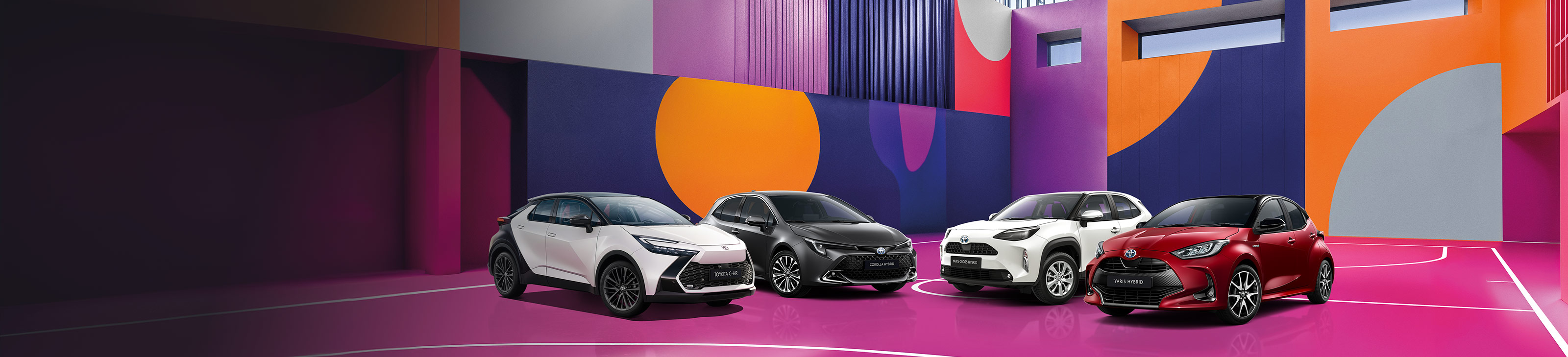 Ein weißer Toyota C-HR, ein grauer Corolla, ein weißer Yaris Cross und ein roter Yaris stehen auf einem bunten, mit lilanen, roten und blauen Mustern versehenen Basketballplatzes