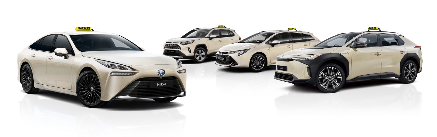 Eine Reihe von vier beigefarbenen Toyota-Taxis, darunter der Toyota Mirai und weitere Hybridmodelle, die die Vielfalt umweltfreundlicher Transportmöglichkeiten zeigen.