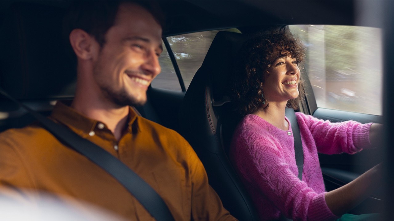 Frau und Mann sitzen lächelnd in einem Toyota