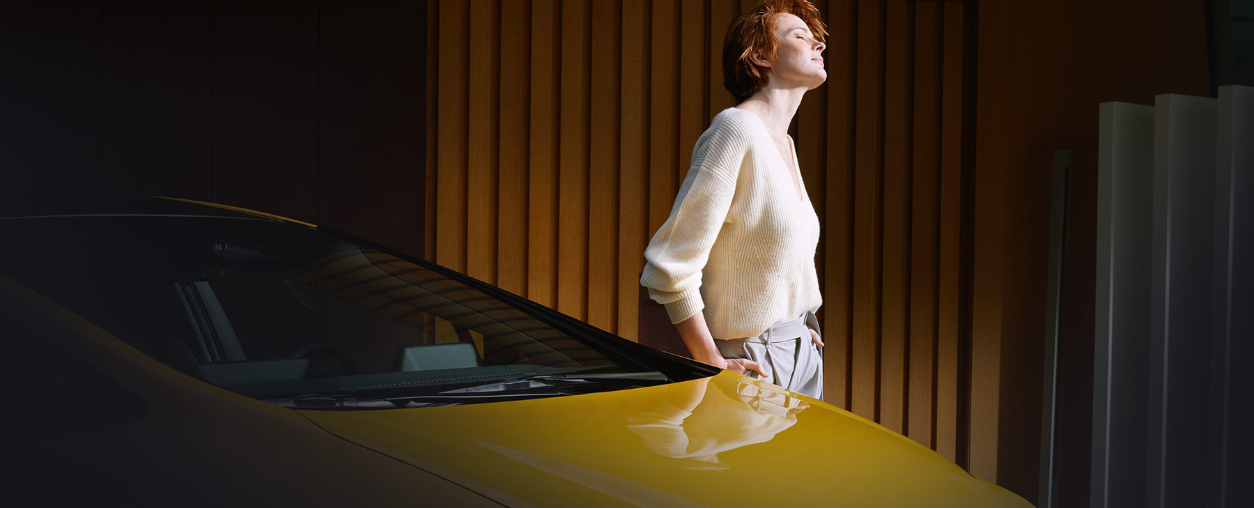 Frau steht neben einem gelben Toyota Prius und genießt die Sonne