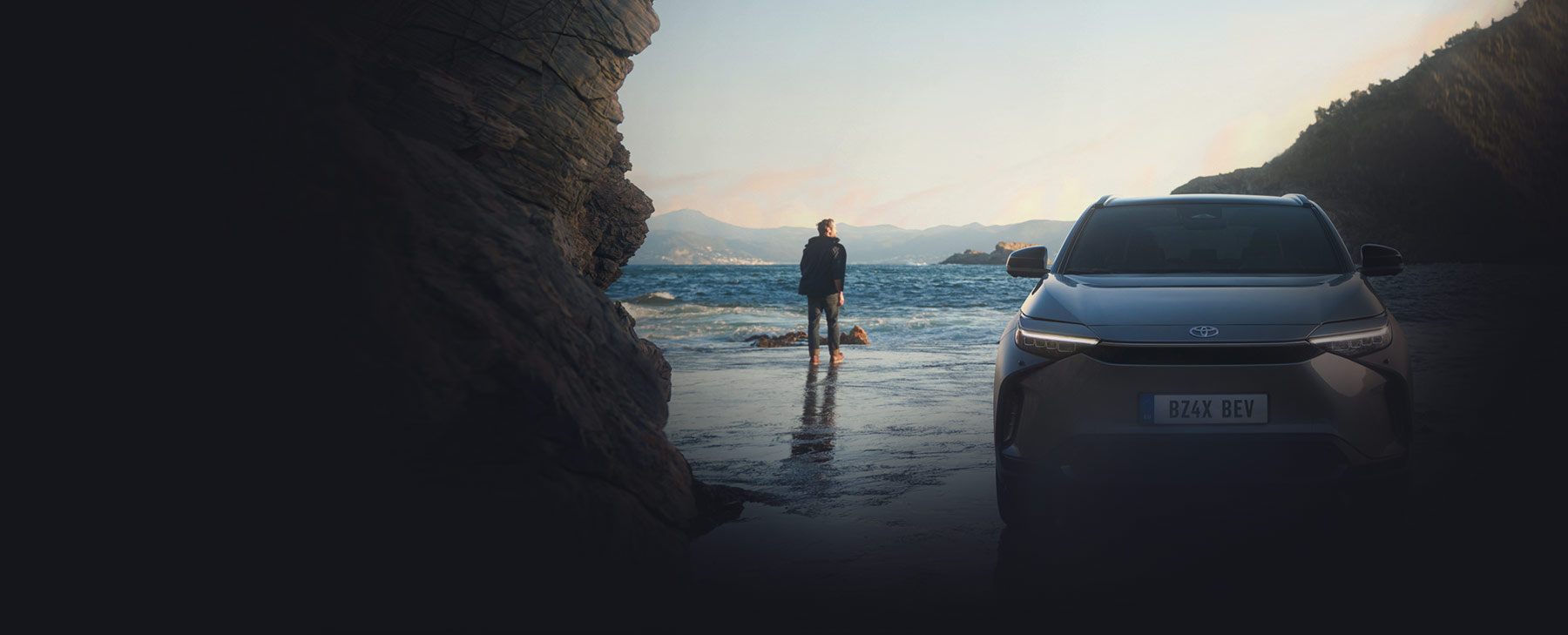 Mann steht neben seinem Auto am Strand