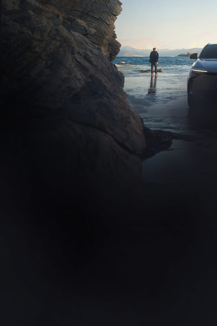 Mann steht neben seinem Auto am Strand