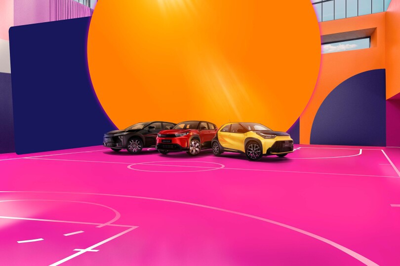 Drei Fahrzeuge von Toyota stehen auf einem pinken Basketballfeld. Die Wände sind in bunten Formen dekoriert.