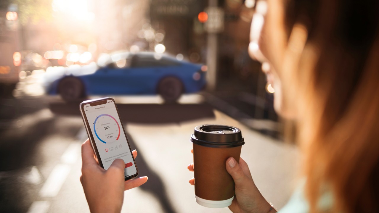 Person hält Smartphone und Kaffeebecher in der Hand