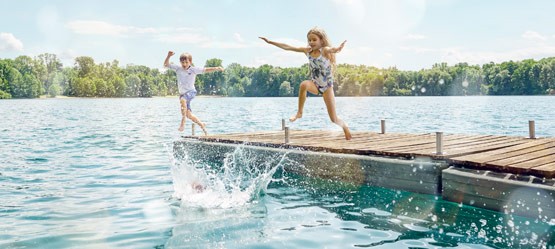Kinder auf einem Steg springen ins Wasser