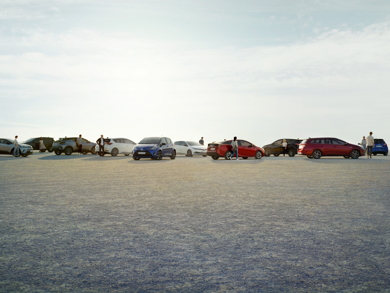 10 verschiedene Toyota Modelle stehen am Horizont, die Fahrer und Fahrerinnen stehen daneben.