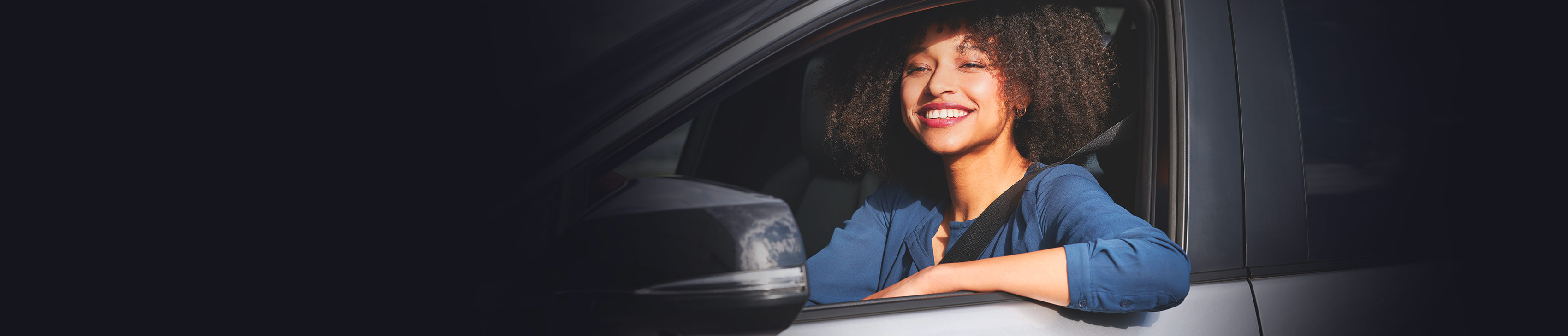 Frau schaut lächelnd aus einem Auto heraus