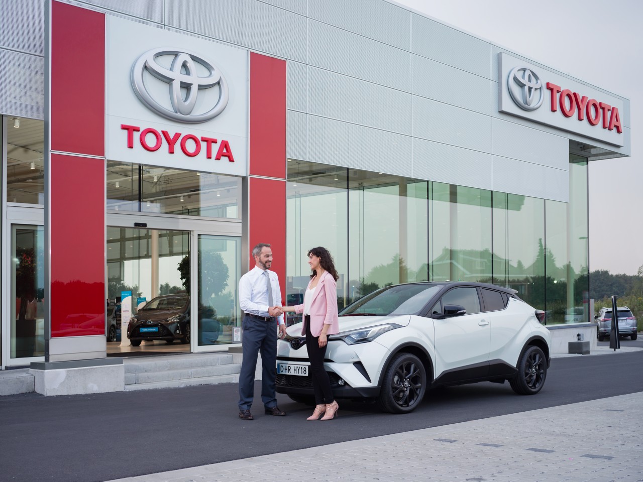 Toyota Vertragshändler und eine Kundin vor einem Toyota C-HR