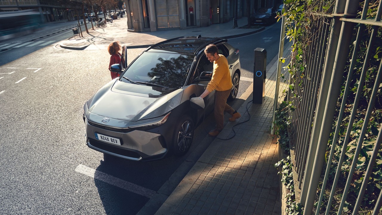 Zwei Personen steigen in den Toyota Bz4x, welches geparkt an einer Elektro-Zapfsäule steht.