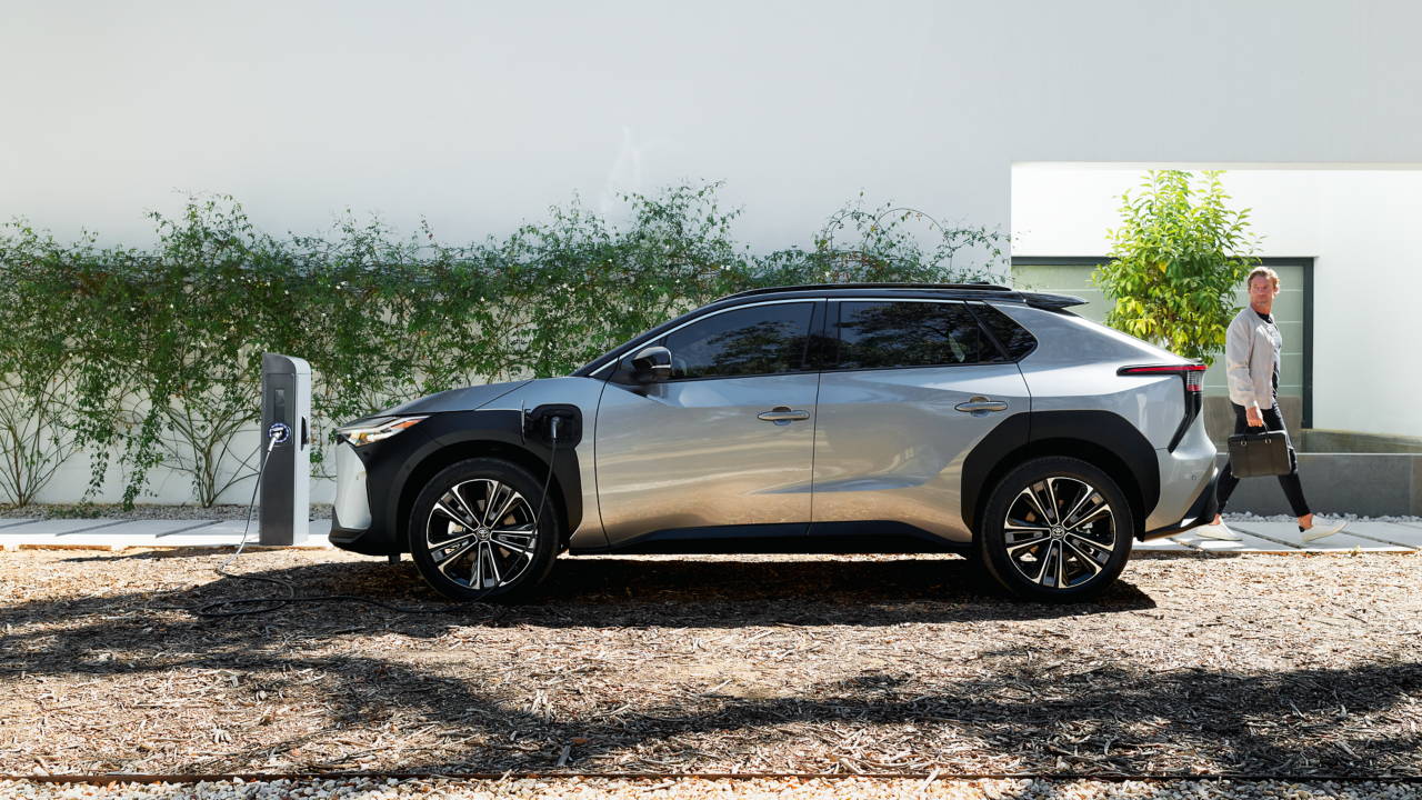 Toyota Bz4x steht geparkt an einer Zapfsäule. Dahinter ein Mann.