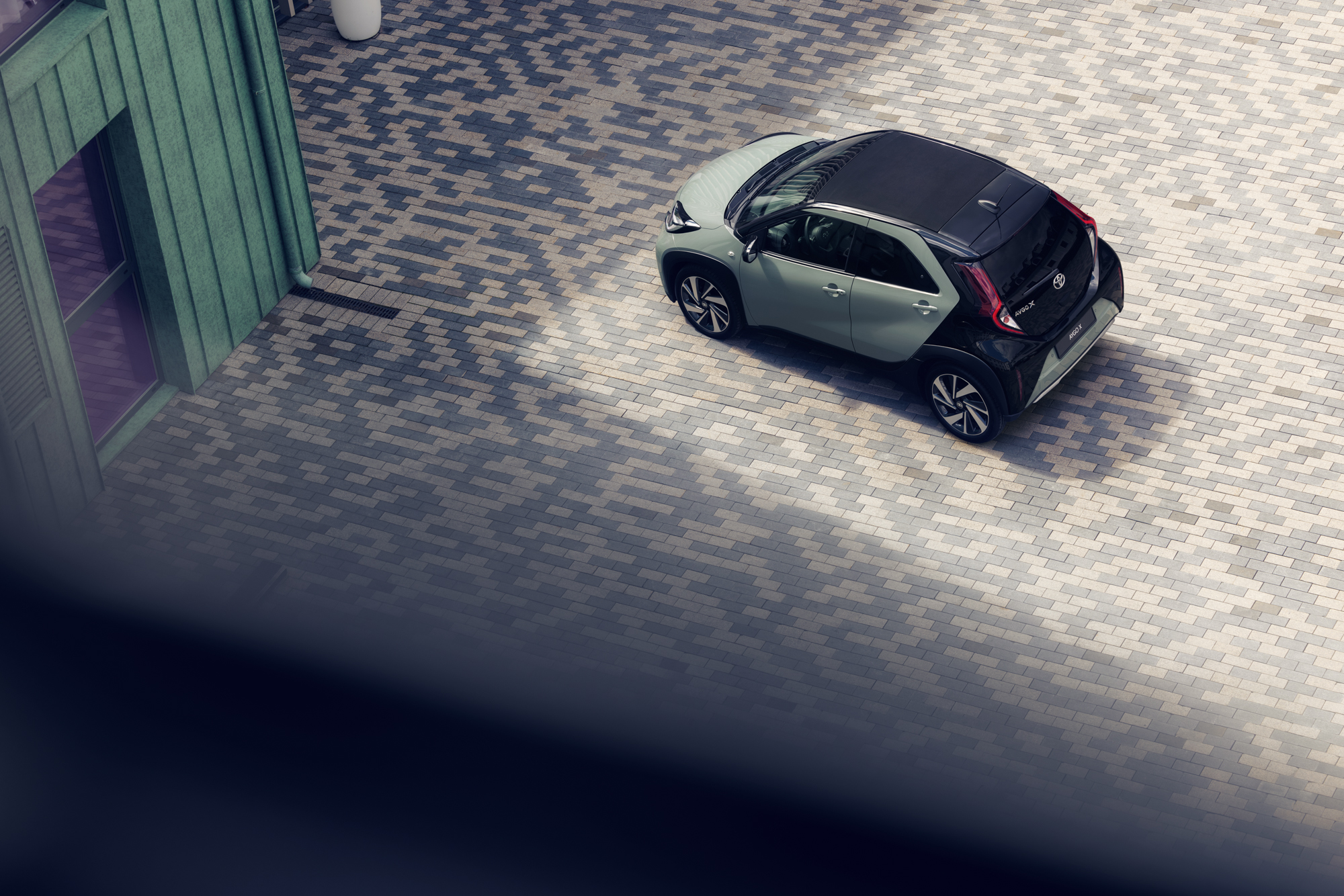 Ansicht von oben auf einen grünen Aygo X vor einer Garage 