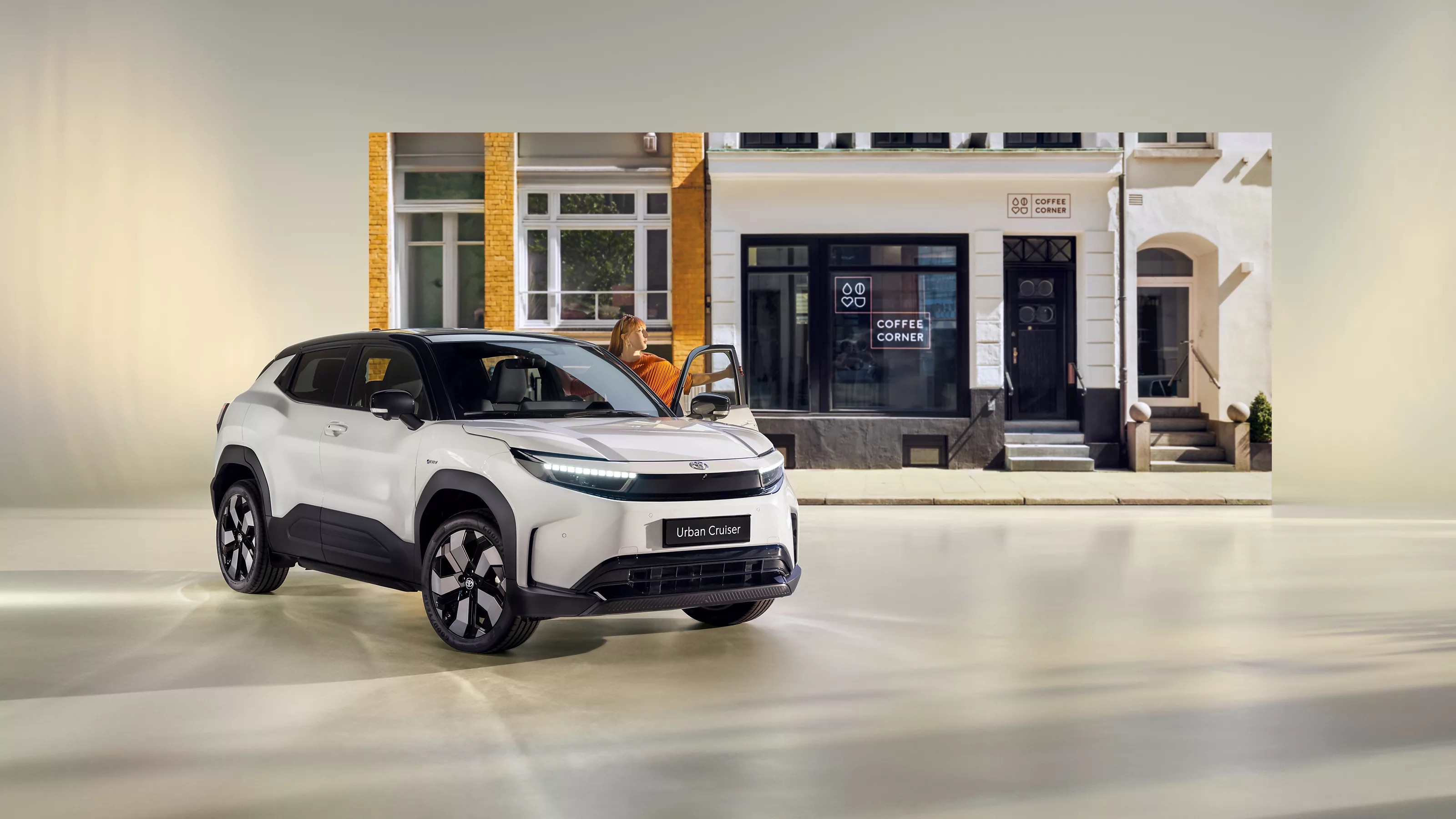 Toyota Urban Cruiser vor modernem Café – kompaktes SUV mit futuristischem Design in urbanem Umfeld, ideal für die Stadt, moderne Mobilität mit Lifestyle-Faktor.