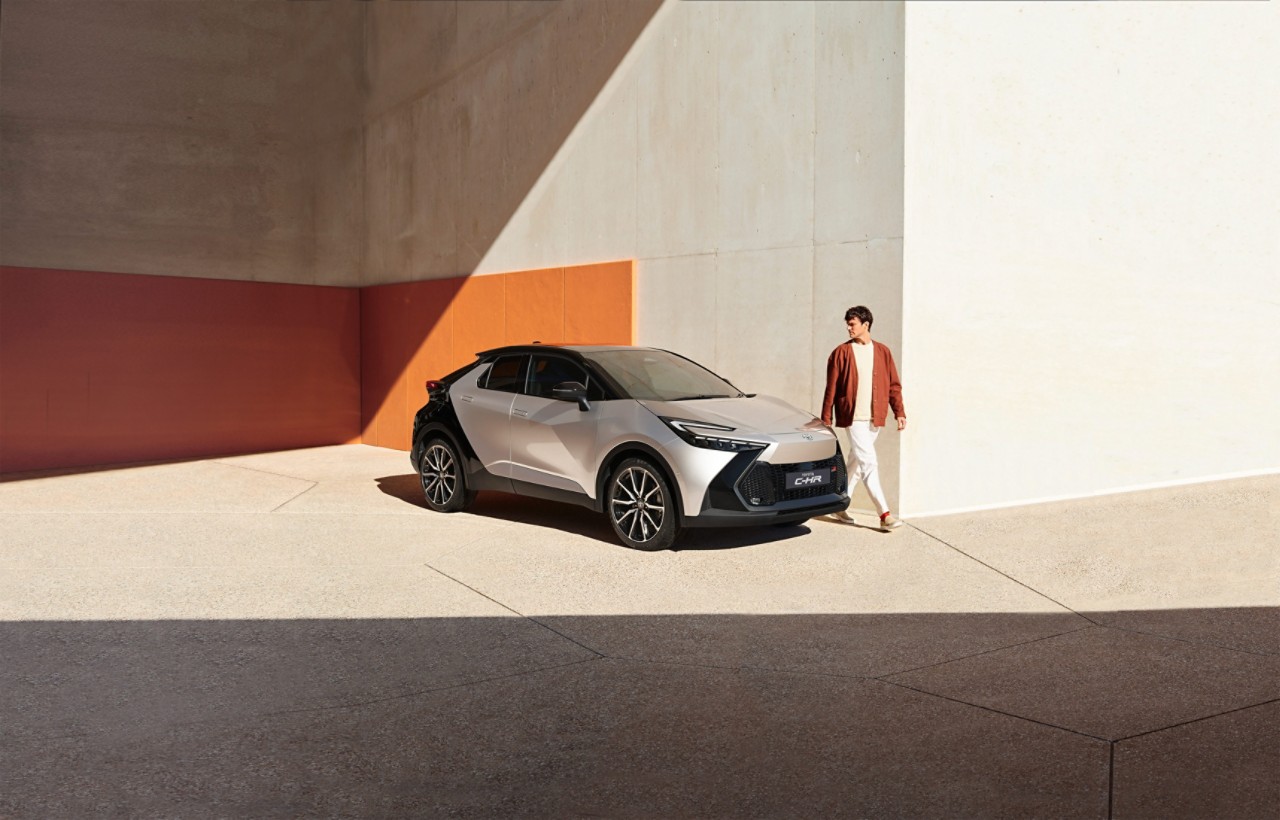 silberner Toyota C-HR mit Mann vor Wand