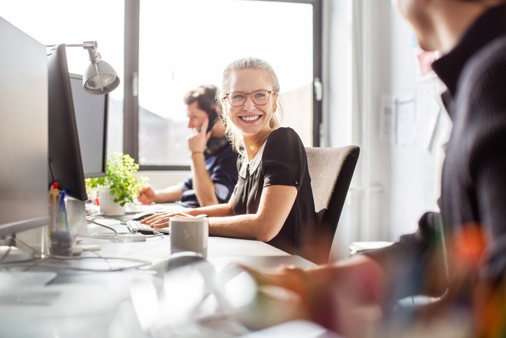 Lachende Praktikantin am Arbeitsplatz