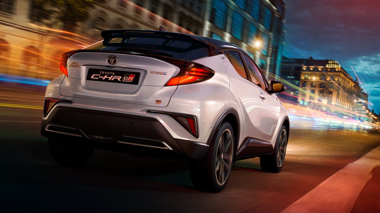 Toyota C-HR fährt in der Dämmerung eine Straße entlang
