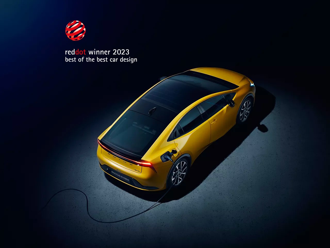 Toyota Prius Plug In vor einem dunklen Hintergund mit Reddot winner 2023 Logo