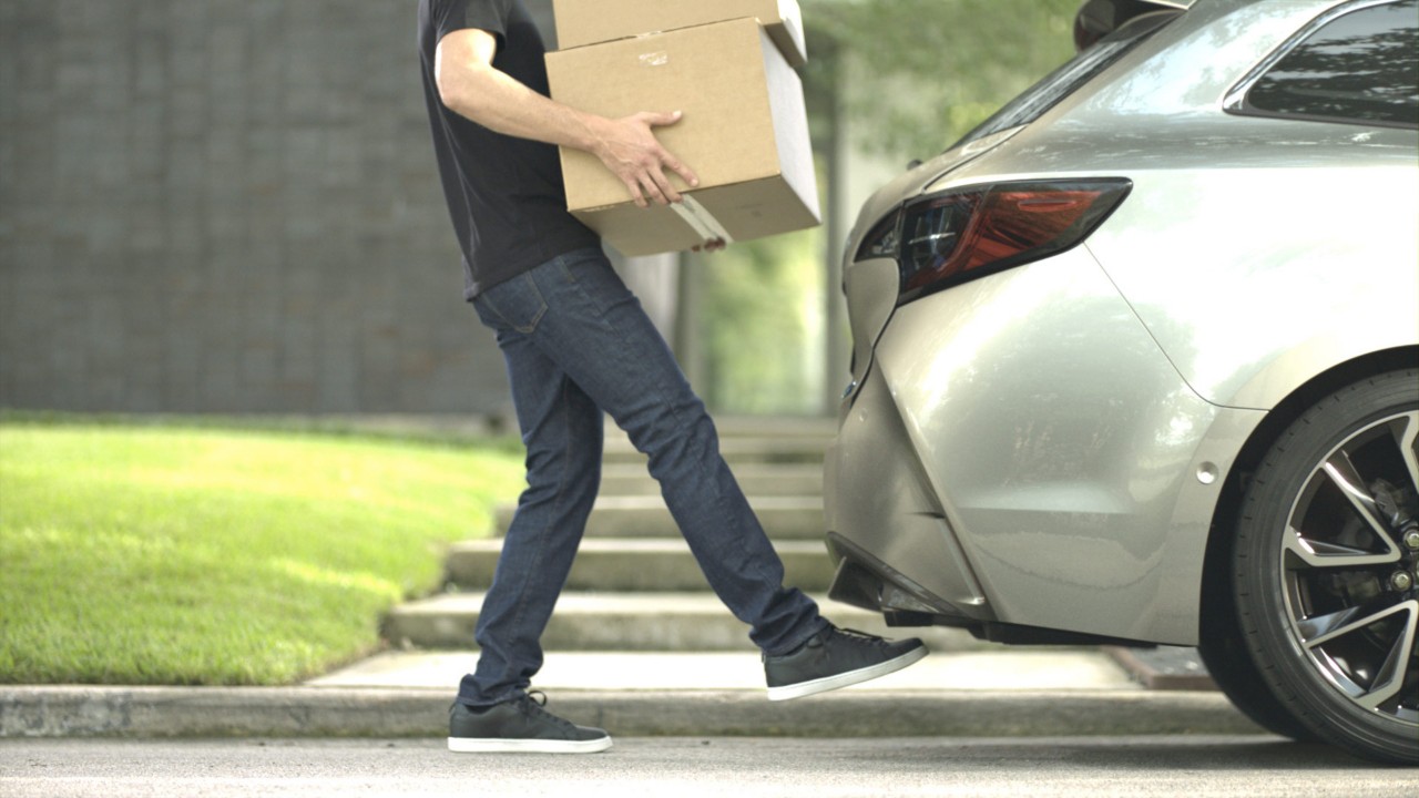 Ein Mann öffnet den Kofferraum eines Toyota Corolla Touring Sports mit dem Fuß-Sensor
