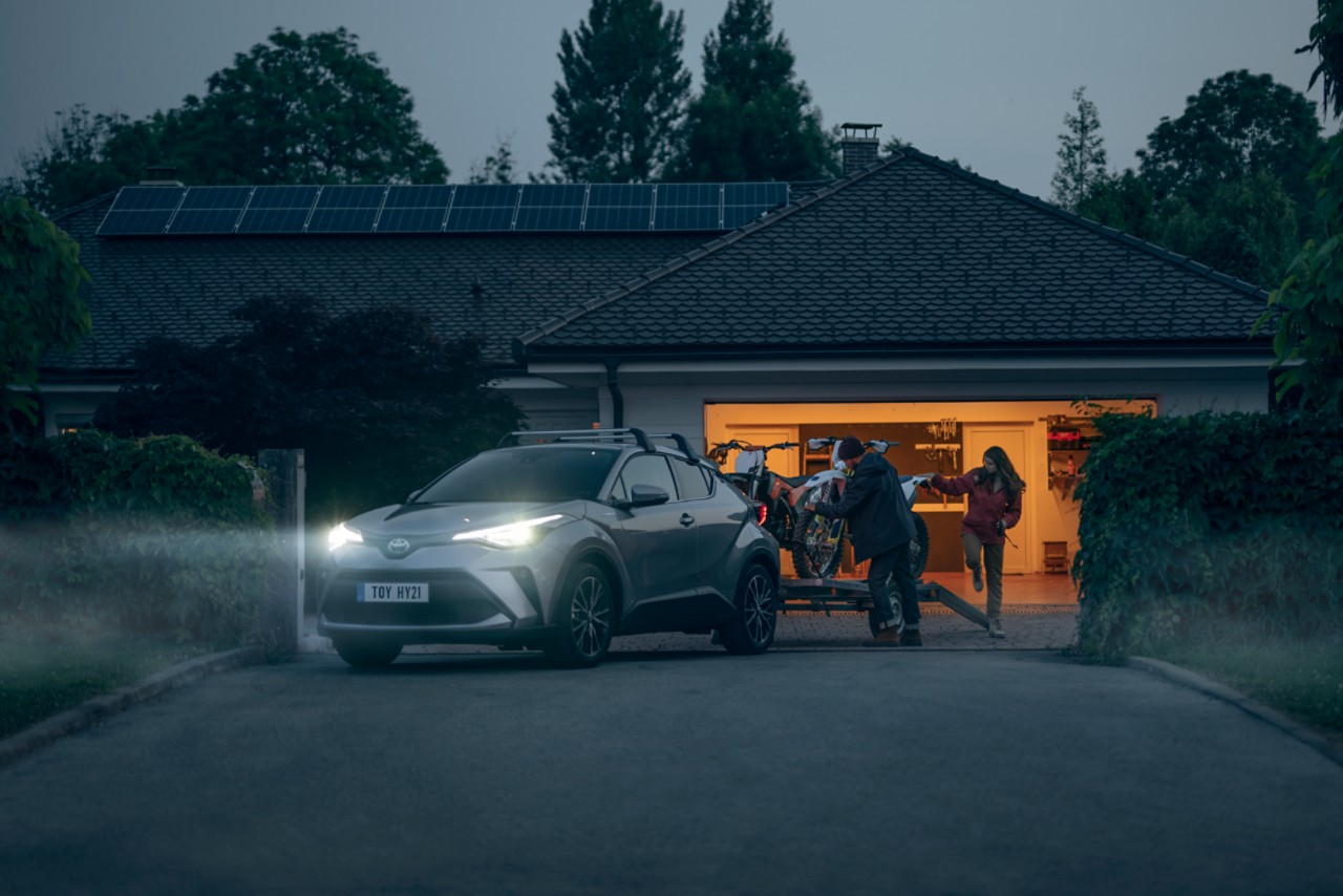 Ein Crossover mit einem Anhänger steht vor einer Garage 