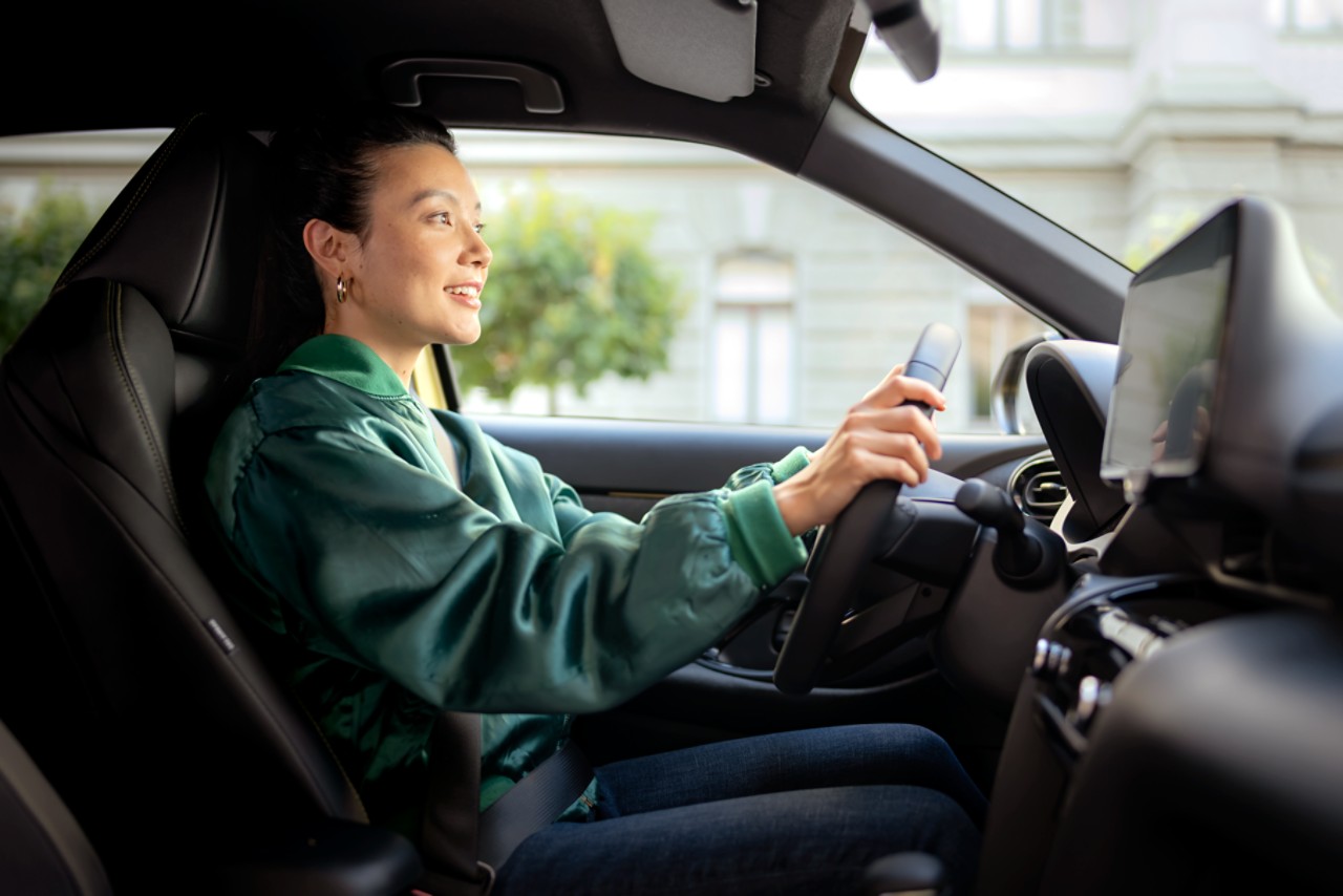 Fahrerin am Steuer schaut auf ein Infotainment System vor ihr