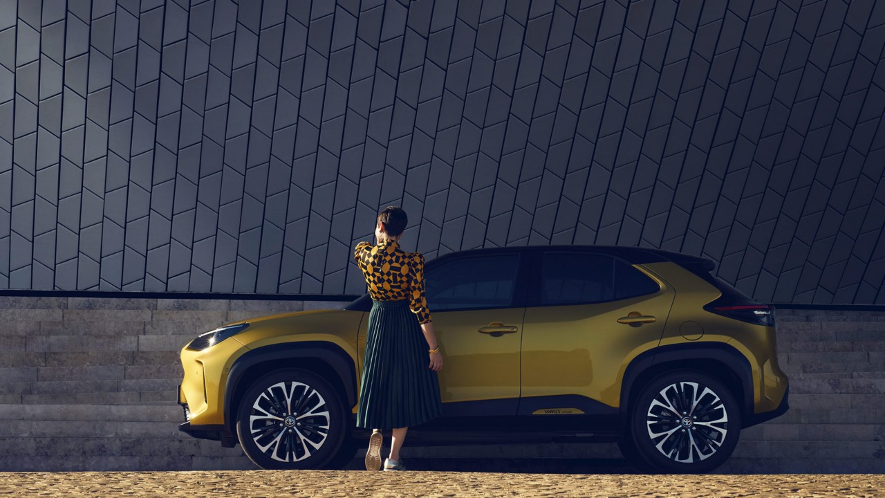 Eine Frau geht auf einen Toyota Yaris Cross zu