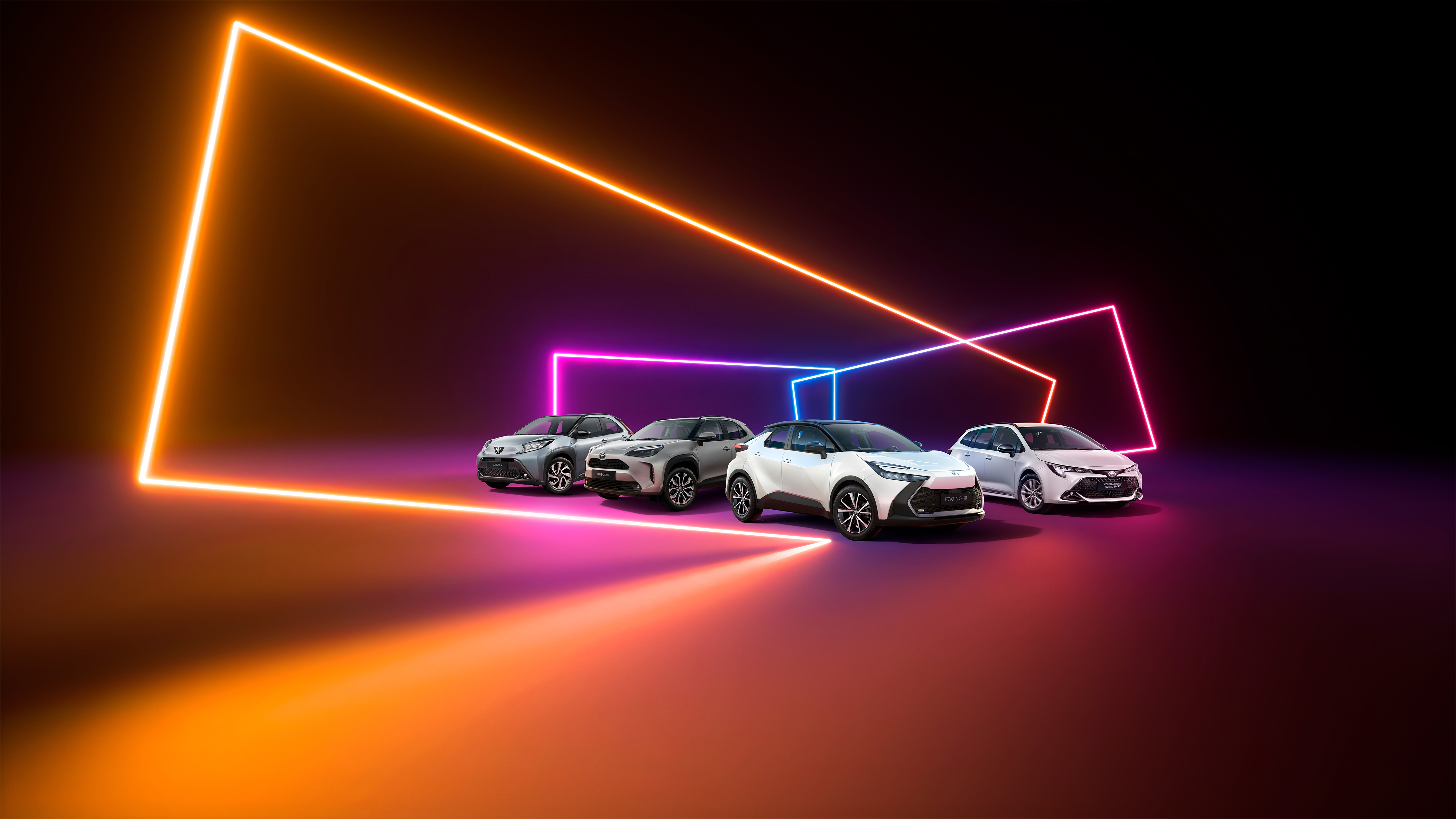 Vier Toyotas stehen auf einem pinken Basketballplatz, der von einer bunt bemalten Wand umgeben ist