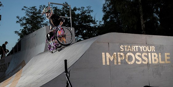 Ein Rollstuhlfahrer fährt eine Halfpipe hinunter