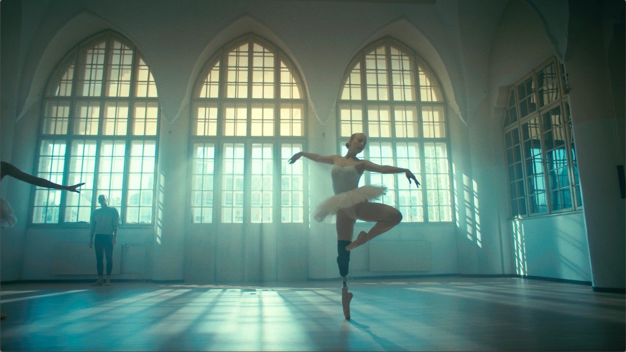 Eine Ballet-Tänzerin mit Fußprotese tanzt in einem mit Licht erfüllten Studio.