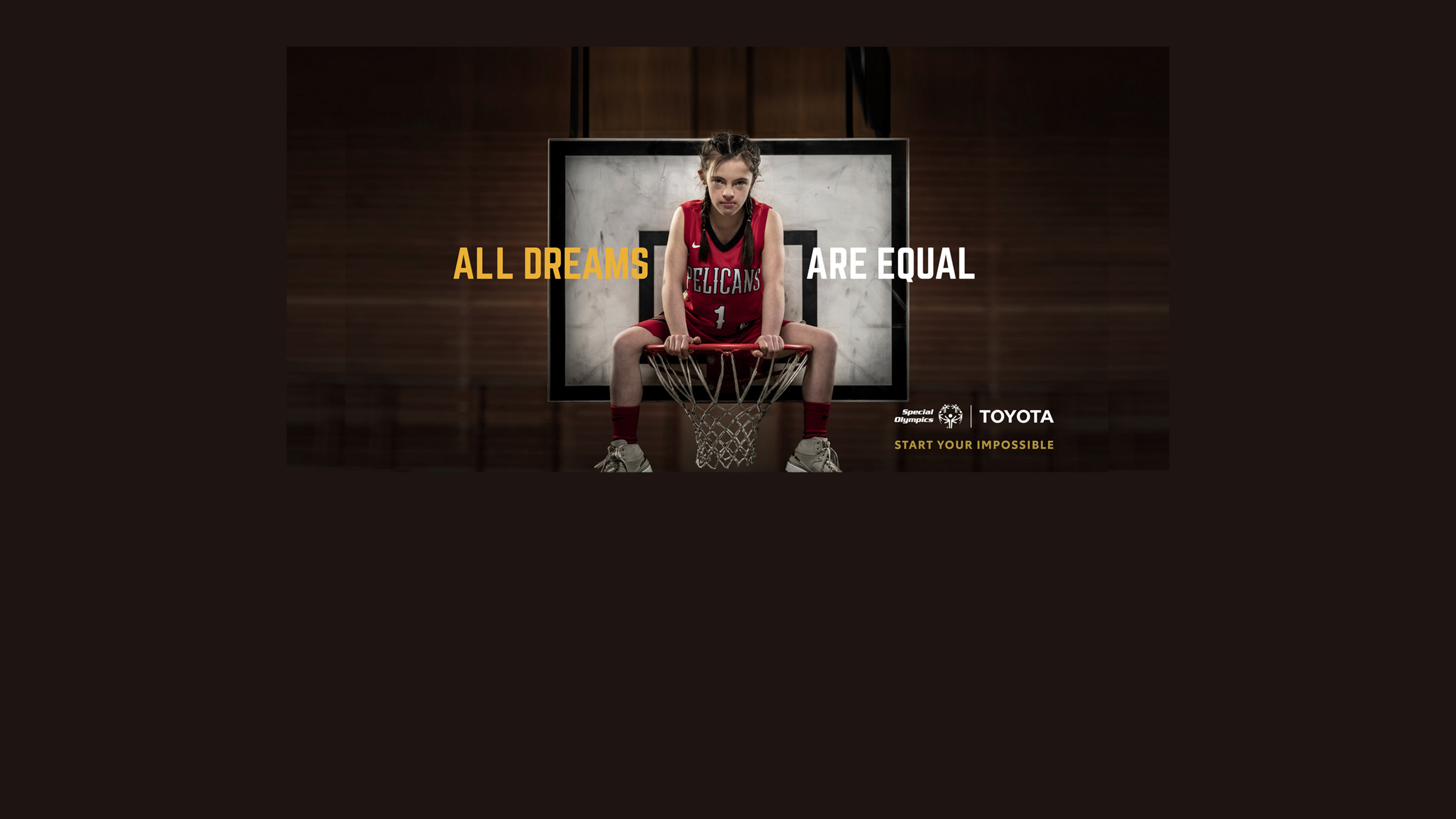 Eine junge Basketballspielerin mit Trisomie 21 sitzt im Basketballkorb. Titel: All Dreams Are Equal