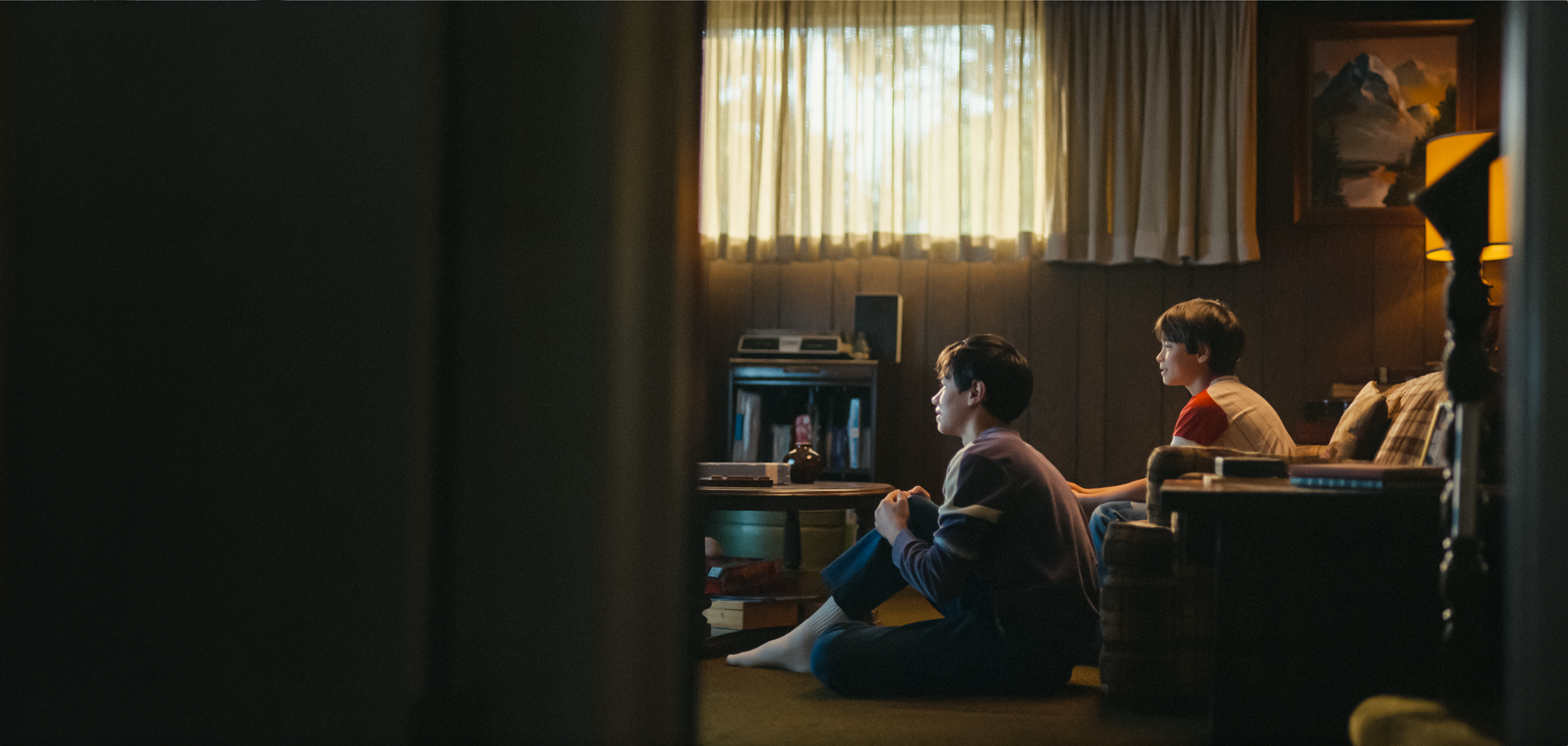 Rückblick auf zwei Brüder, die nebeneinander im Wohnzimmer sitzen und konzentriert Fernsehen schauen.