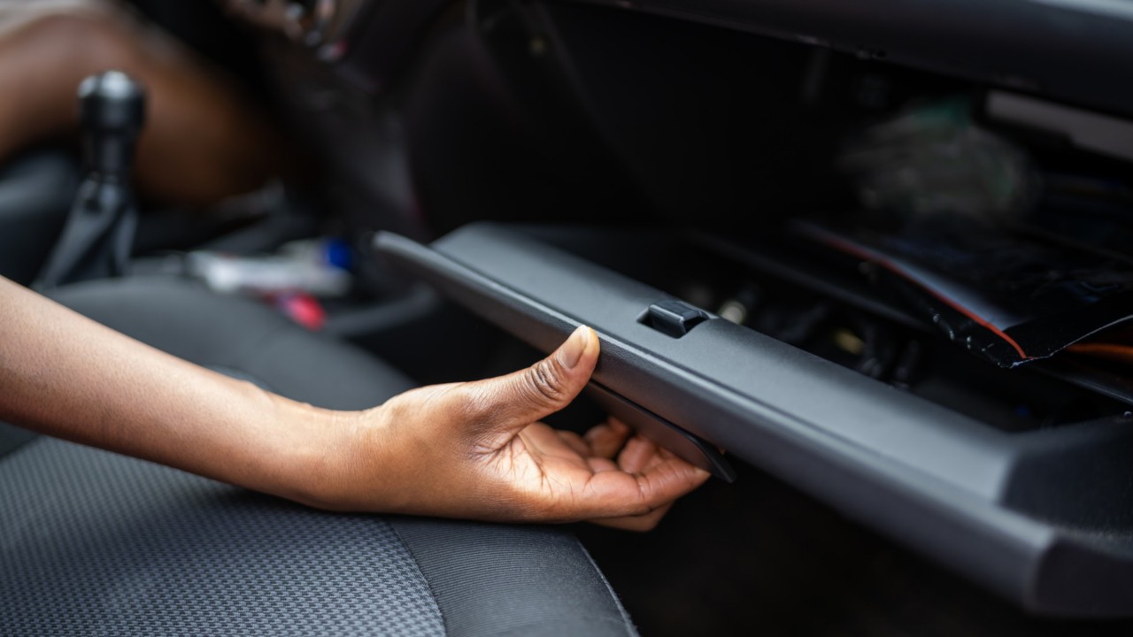 Mann oeffnet Handschuhfach im Auto