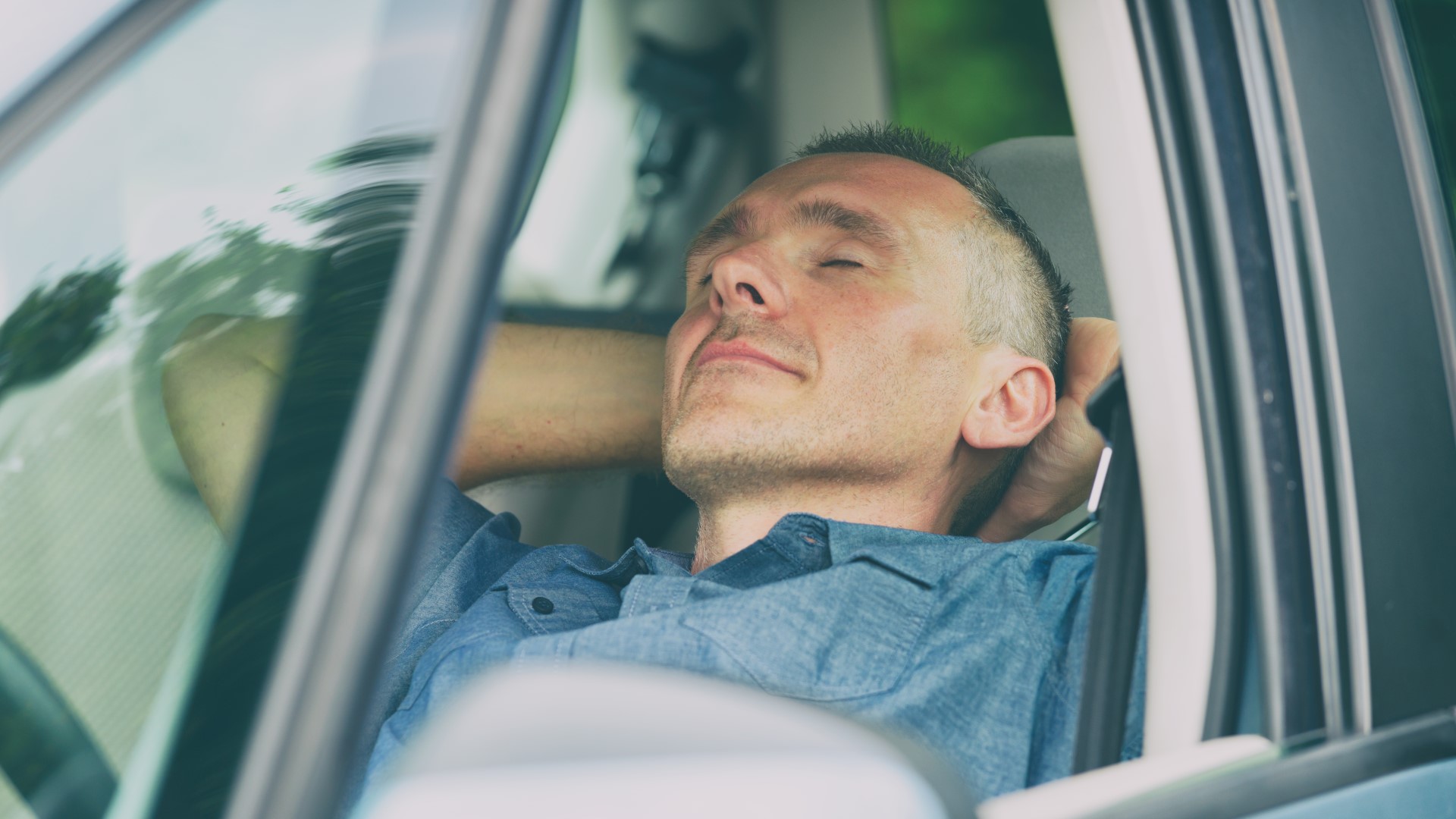 Mann schläft im Auto