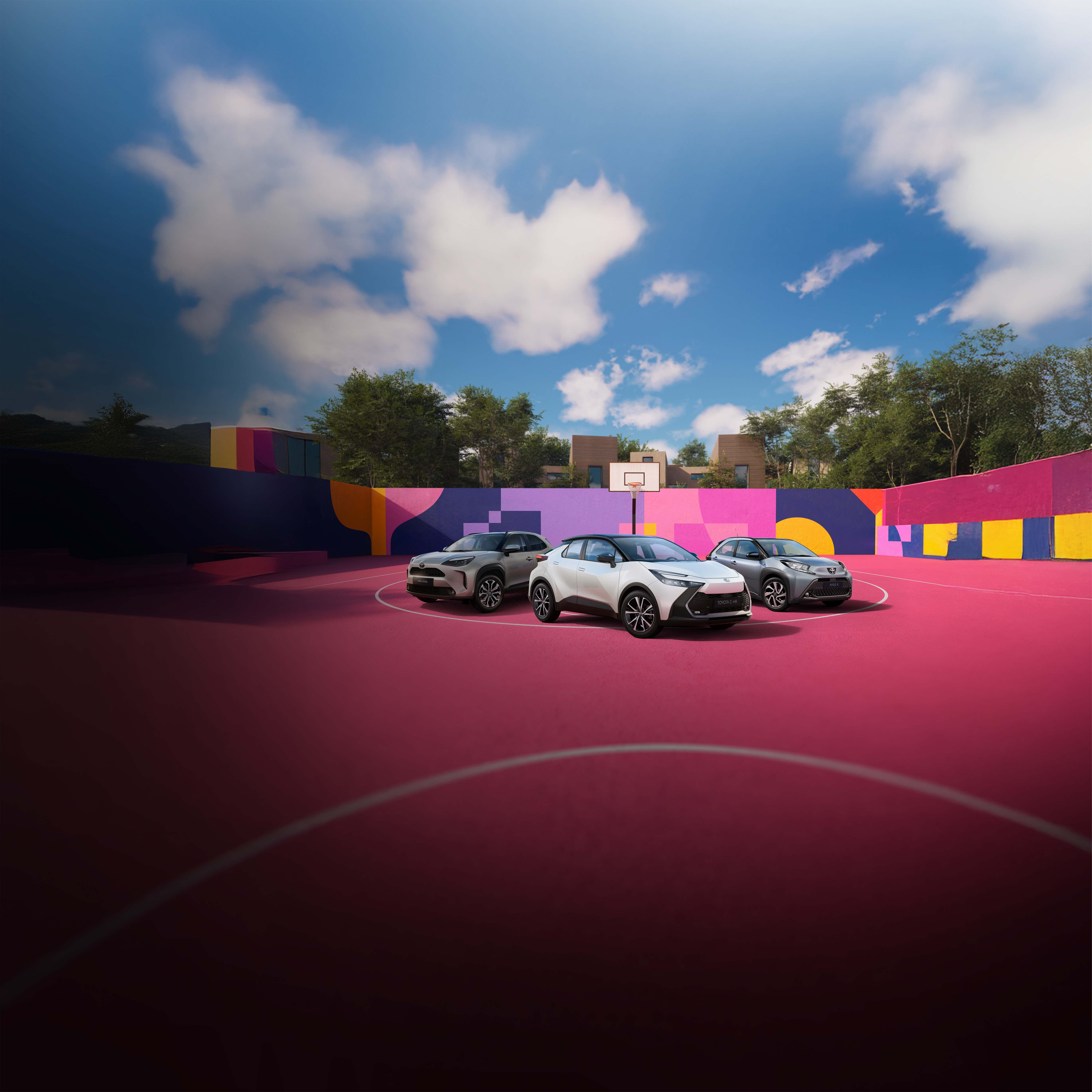 Vier Toyotas stehen auf einem pinken Basketballplatz, der von einer bunt bemalten Wand umgeben ist