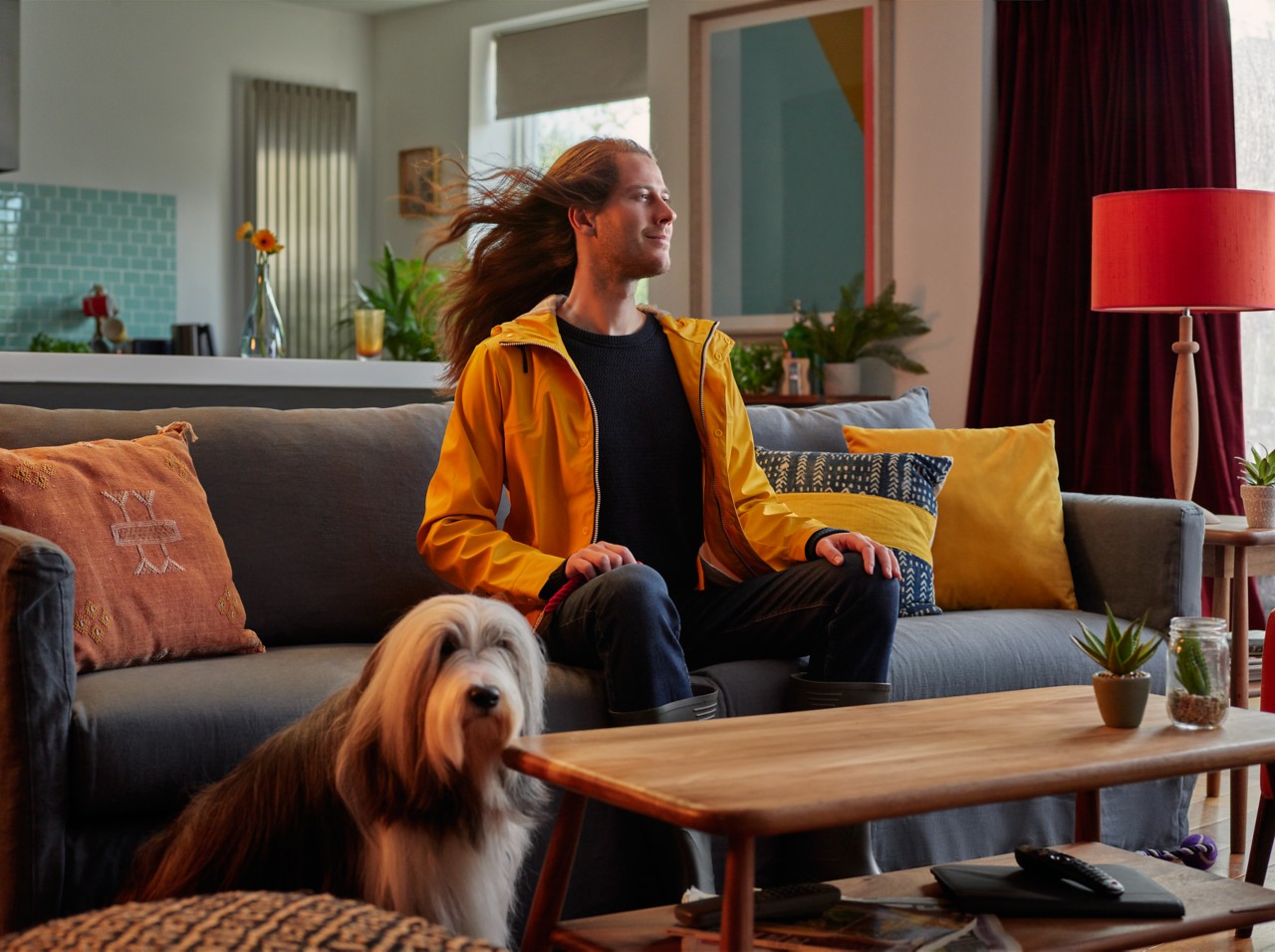 Ein Mann sitzt auf der Couch, daneben sein Hund