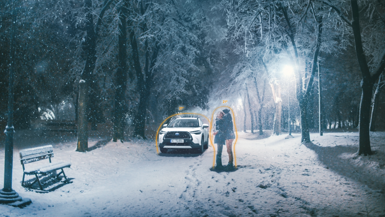 Paar umarmt sich in Winterlandschaft, gelber Toyota C-HR im Hintergrund