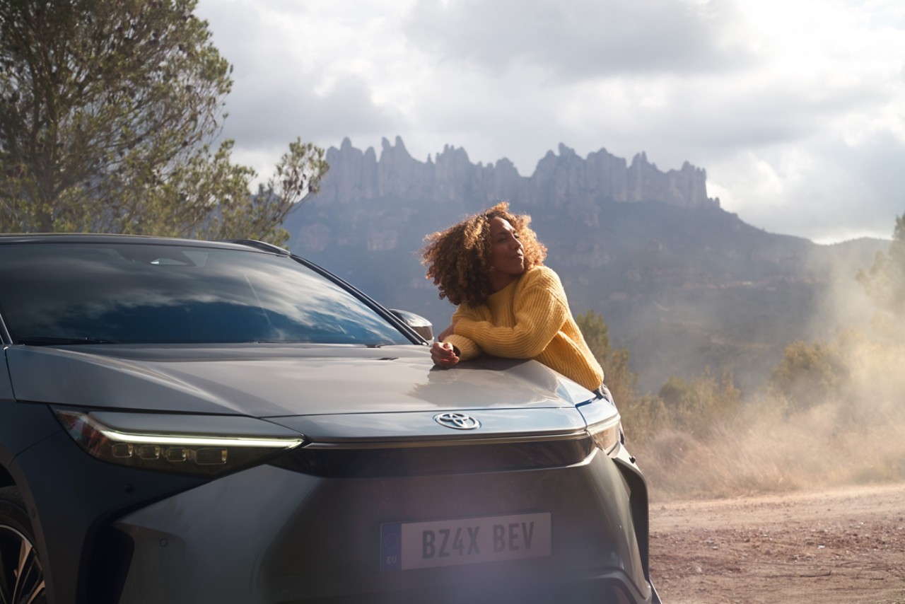 Eine Person lehnt sich an die Motorhaube eines grauen Toyota bZ4X